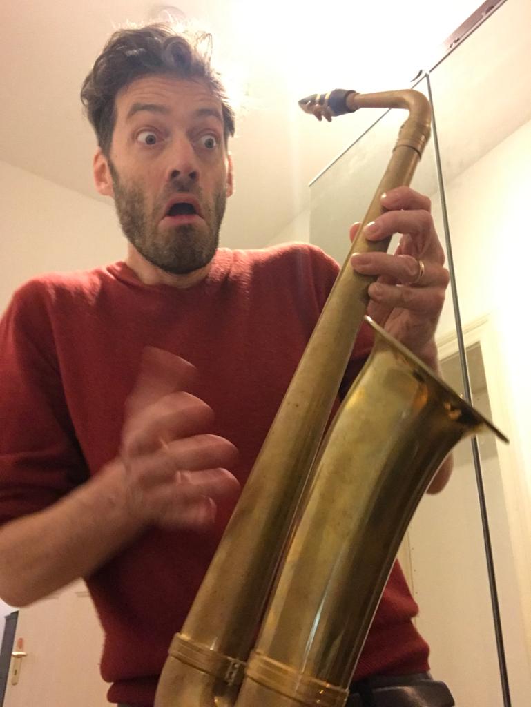 Christian blickt erstaunt auf das Saxophon ohne Tasten, das er in seinen Händen hält.